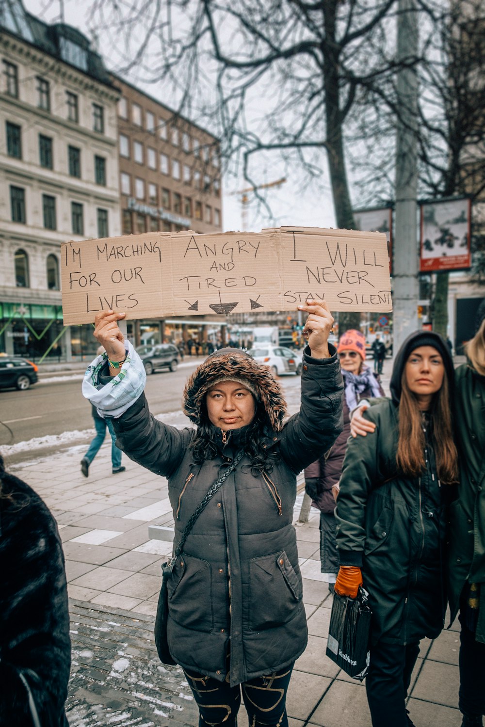 woman standing and raising board with I'm Marching angry four our loves, Angry and tired. And I will never stay silent