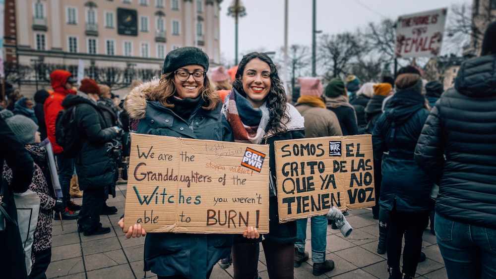 two women holding signages during daytime
