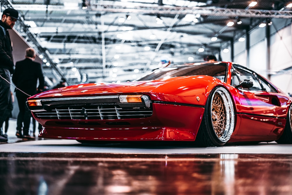 man standing beside red coupe