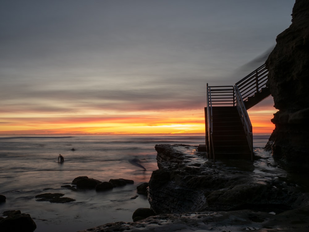 silhouette photography of person on body of water near staircase