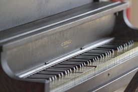 A close-up view of a dark colored piano with visible keys. The manufacturer's name, Kimball, is embossed on the piano. The focus highlights the sleek and polished finish of the instrument.