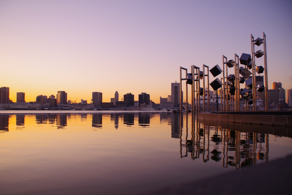 panoramic photography of buildings and towers reflecting on water during sunset