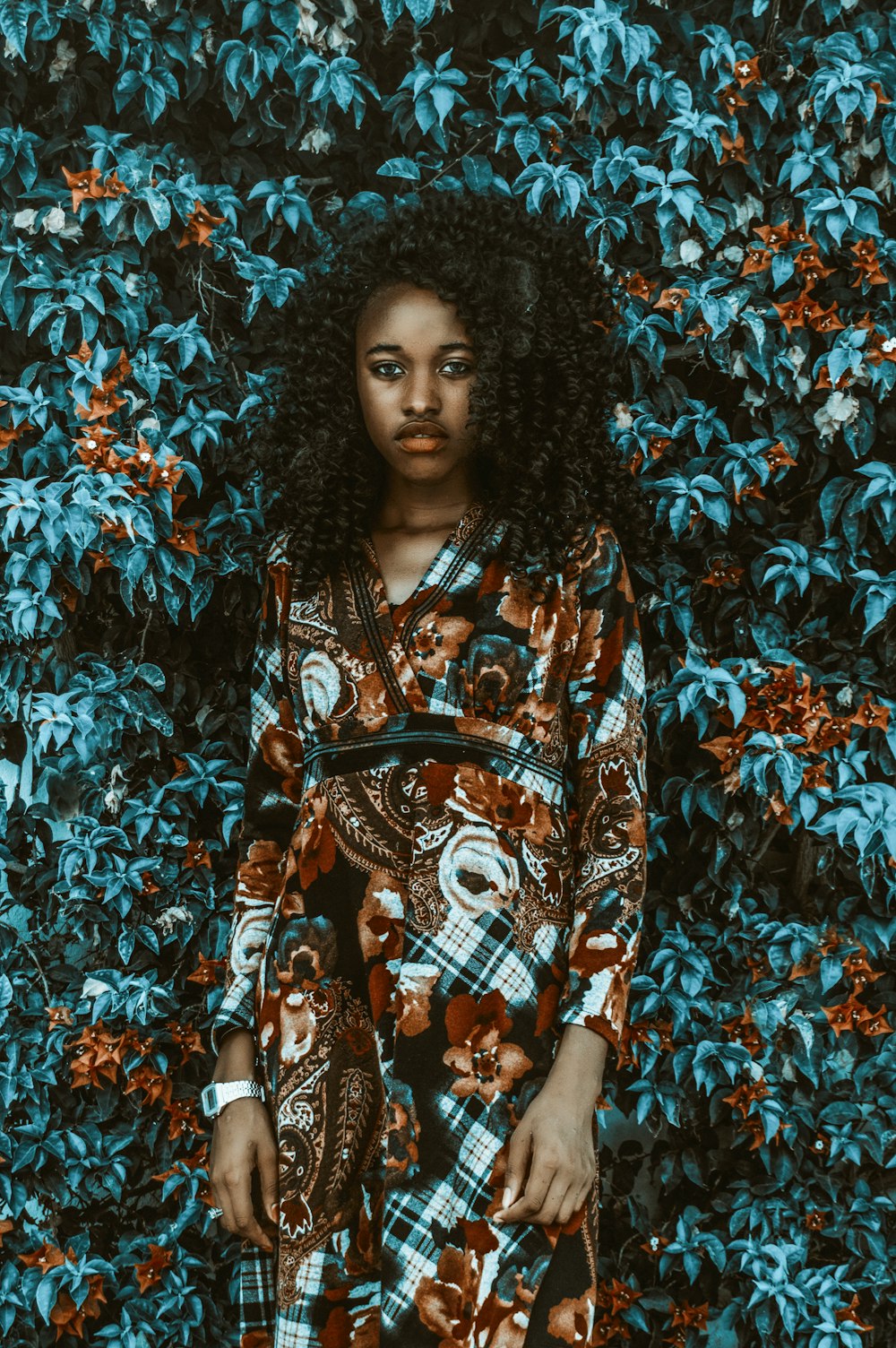 women wearing multicolored long-sleeved dress standing near green-leafed plant