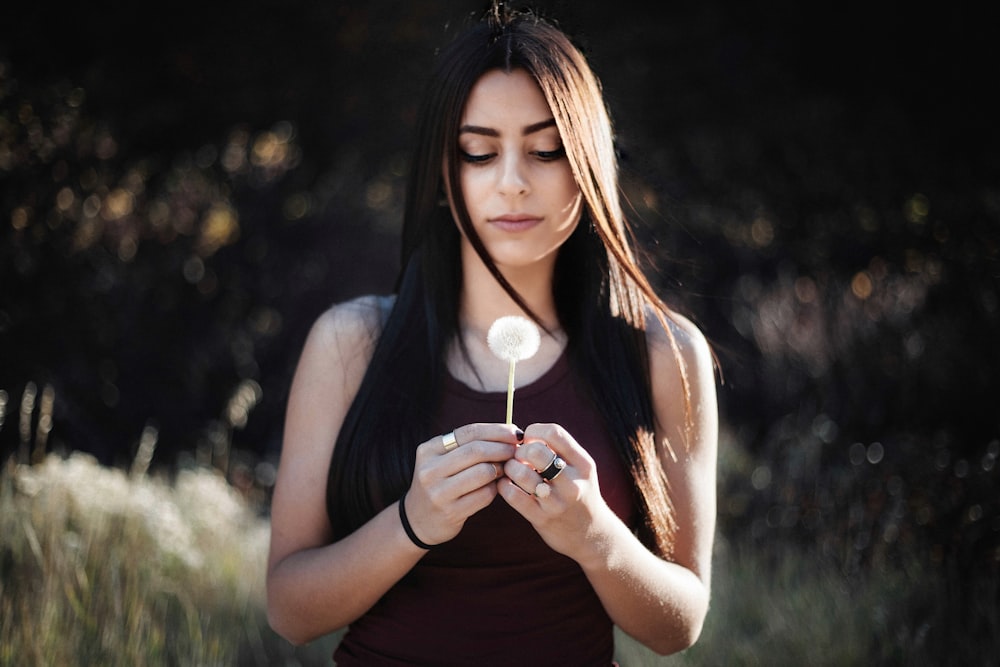 femme tenant une fleur de pissenlit