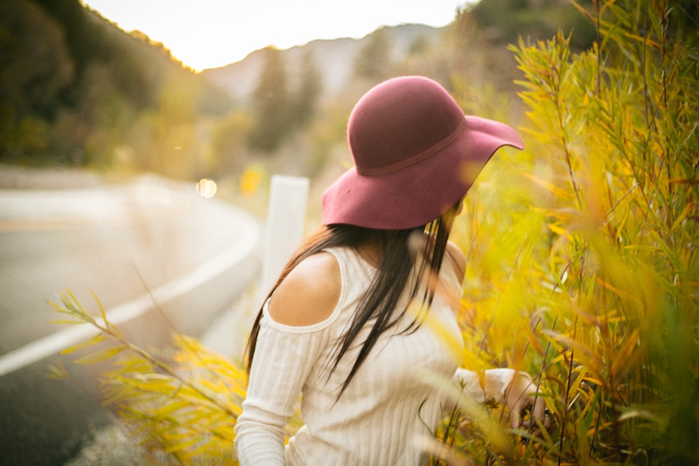 selective focus photography of woman standing beside green-leafed plant