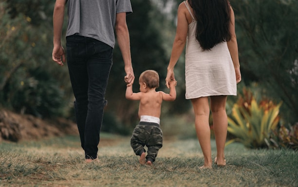 couple walking barefoot with a child at the garden