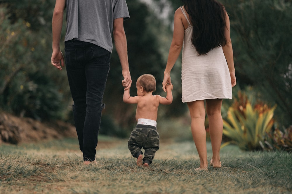 couple walking barefoot with a child at the garden