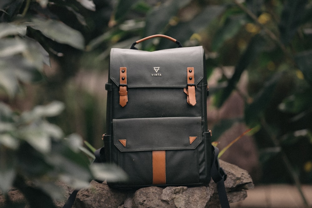 selective focus photography of black and brown leather backpack on rock