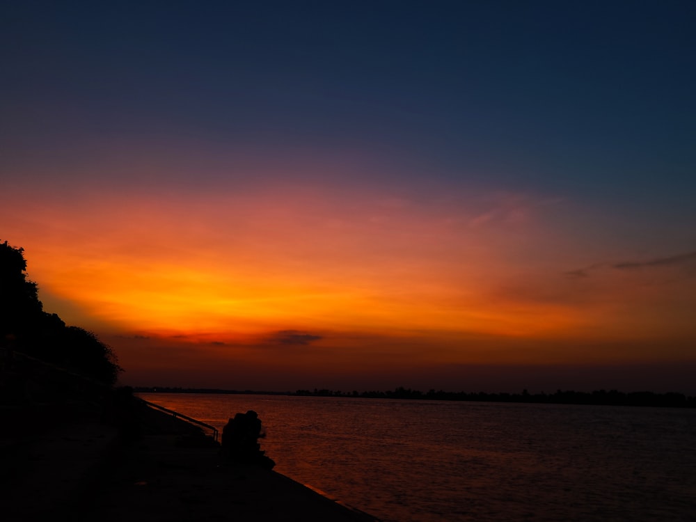 silhouette of field under orange sky