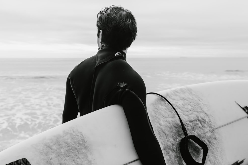 person wearing wet suit holding surfing board