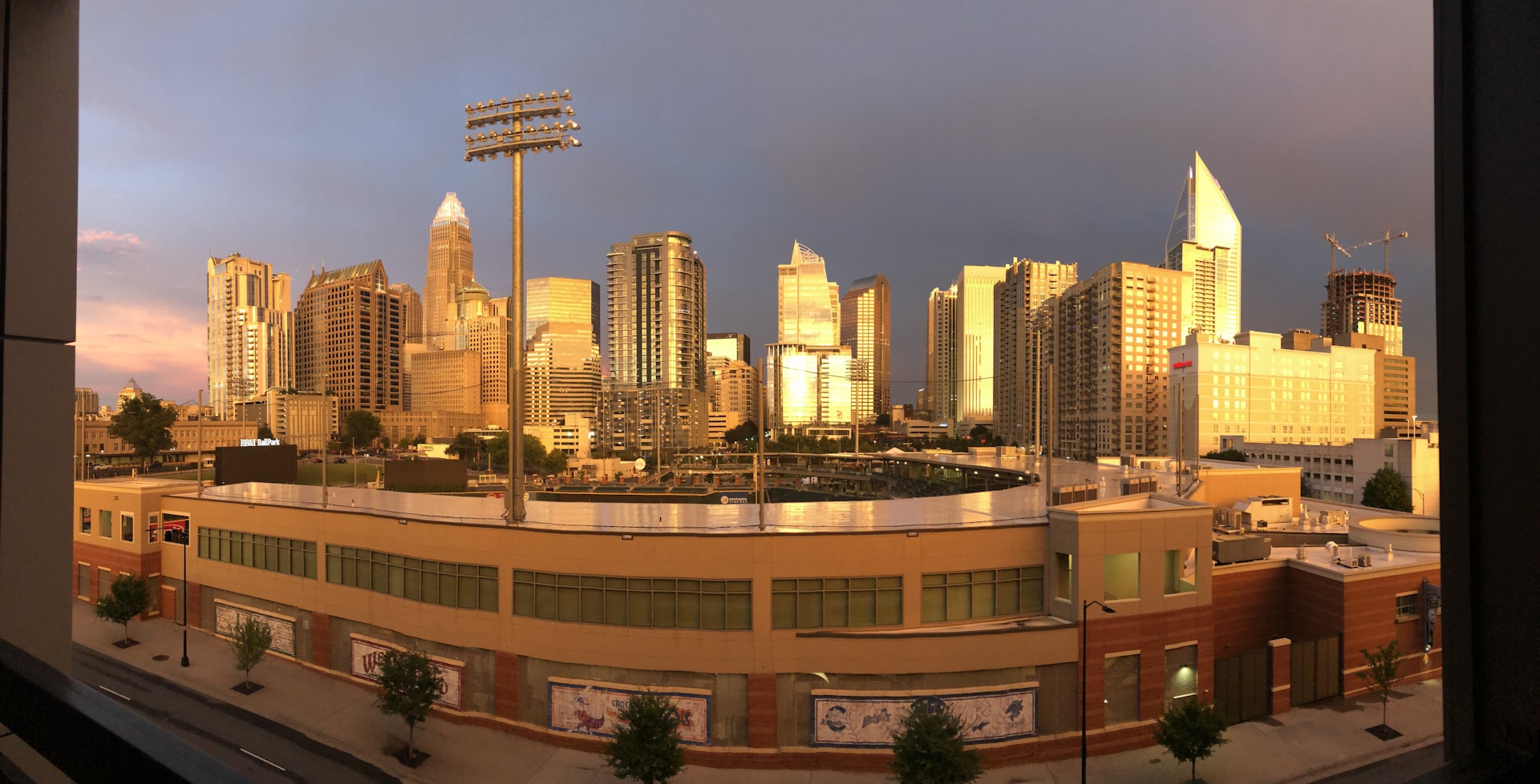 A panoramic aerial photo from a high vantage point, featuring rooftops and busy streets bathed in golden sunlight.