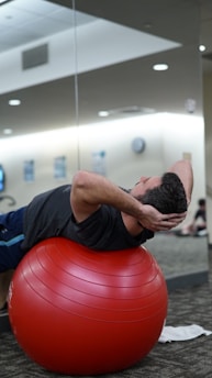 man lying on red stability ball