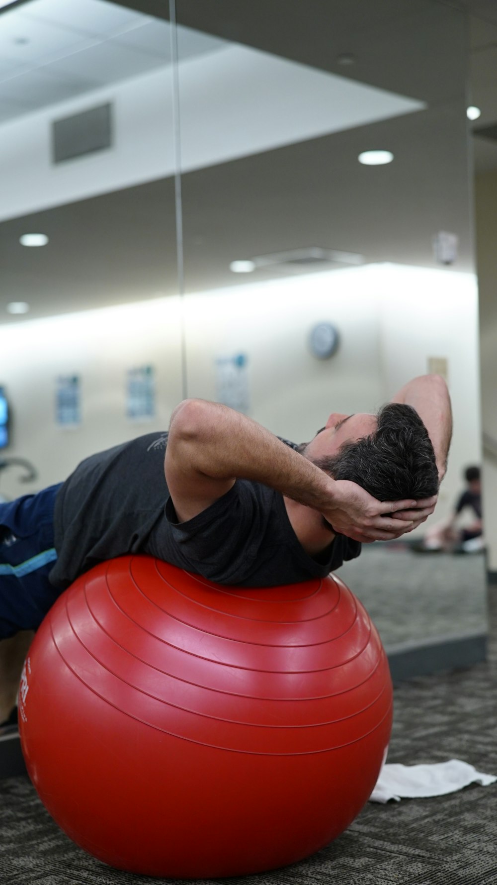 man lying on red stability ball