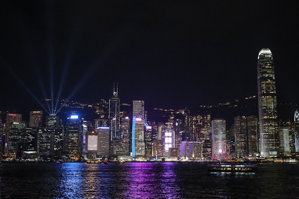 lighted city buildings near calm sea during night time