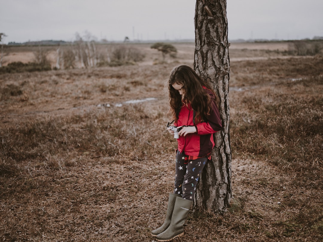 girl leaning on tree during daytime