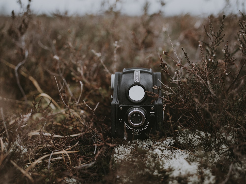 Câmera cinza e preta no campo marrom