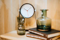 Close-up of a modern table clock with a minimalist design on a marble shelf.