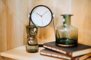 Contemporary desk clock with metal frame and clear glass face on a clean desk.