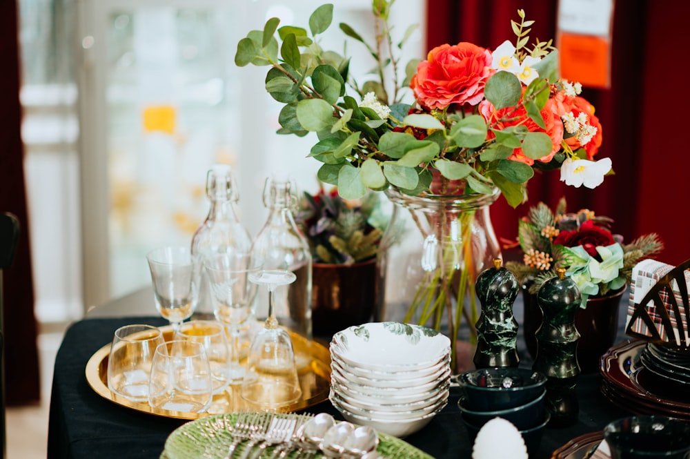 red petaled flowers on table beside plates and bottles