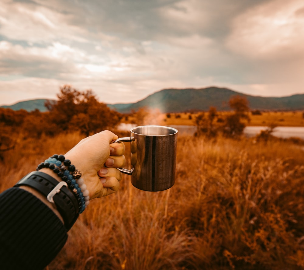 person holding stainless steel cup