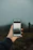 A hand holding a smartphone, capturing a photo of a foggy landscape. The background appears blurred with mist, and the focus is on the phone screen showing a clearer image of the scene.