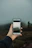 A hand holding a smartphone, capturing a photo of a foggy landscape. The background appears blurred with mist, and the focus is on the phone screen showing a clearer image of the scene.