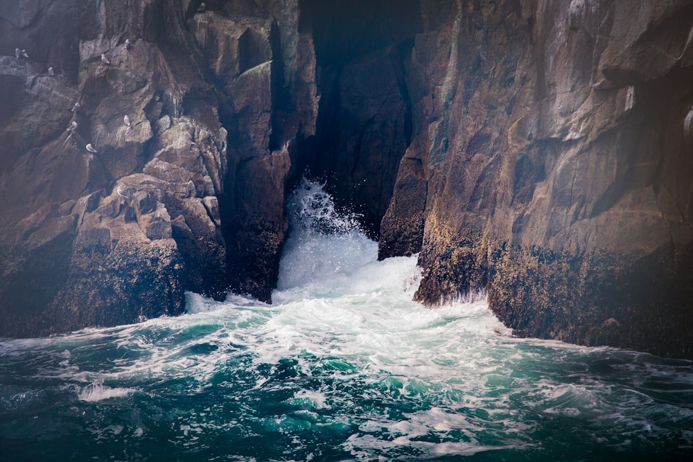 waves crashing on brown rock formation