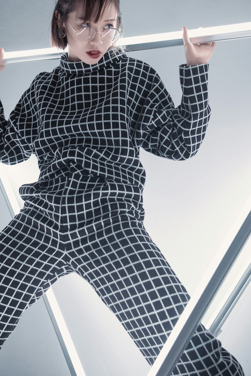 woman in gray and white checked overalls standing on metal bars