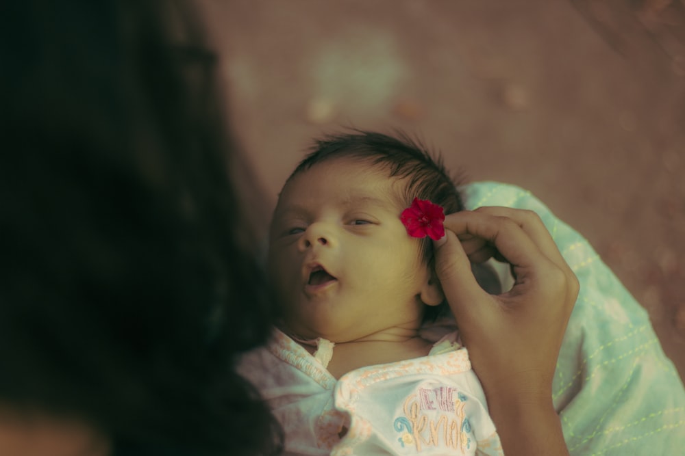 femme mettant une fleur sur la photo de l’oreille du bébé