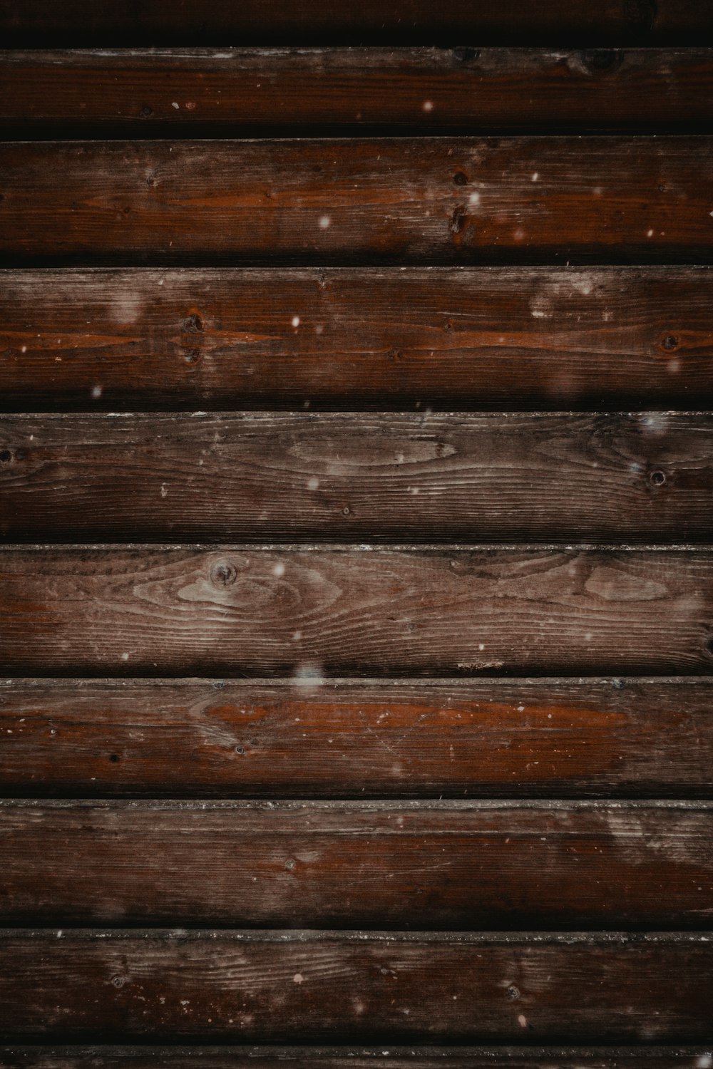 a close up of a wooden wall with snow on it