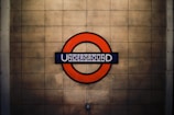 A circular red sign surrounds a blue bar with the word 'UNDERGROUND' in white, set against a beige tiled background.
