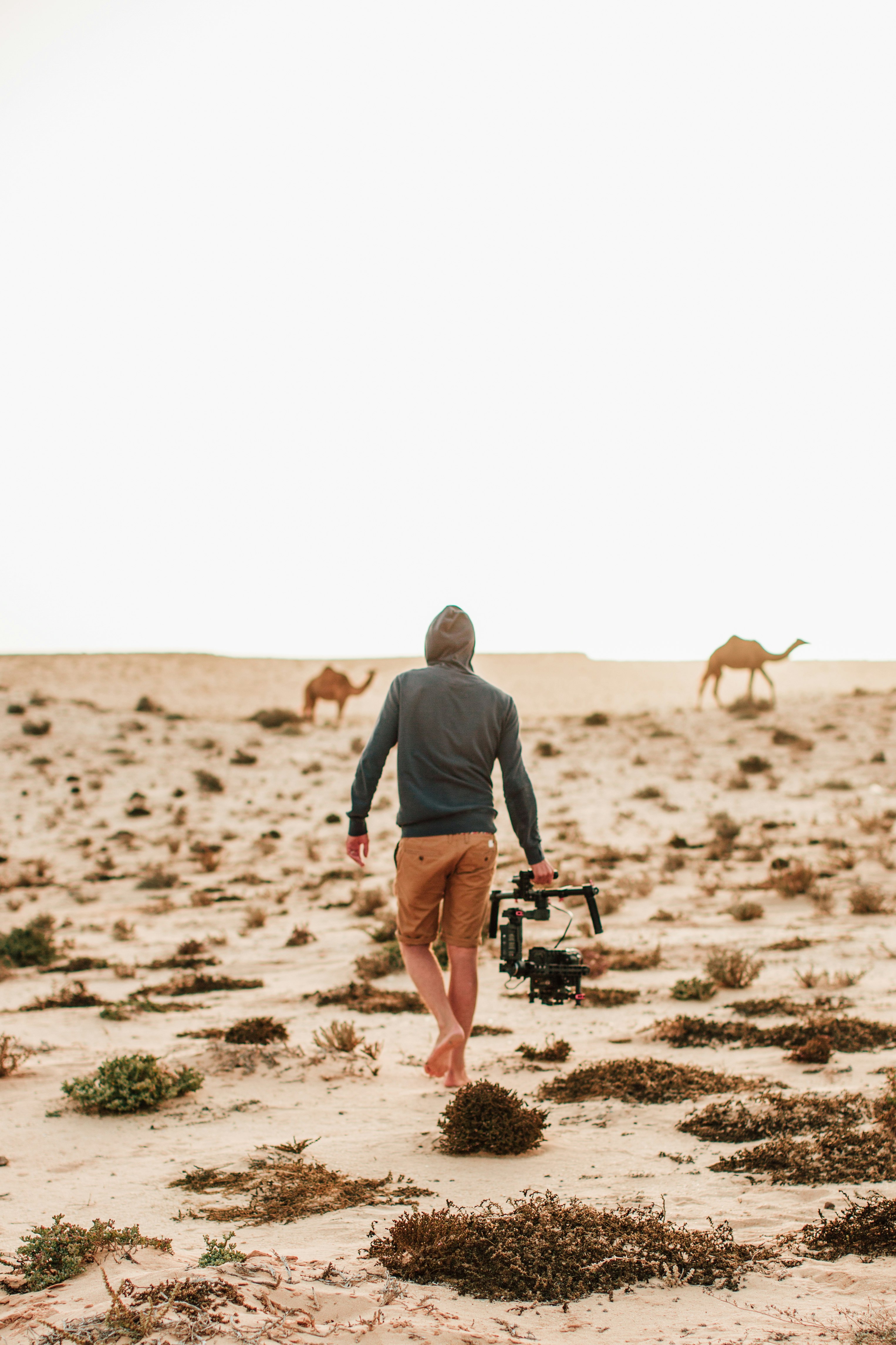 man wearing gray hooded sweater holding gimbal during daytime