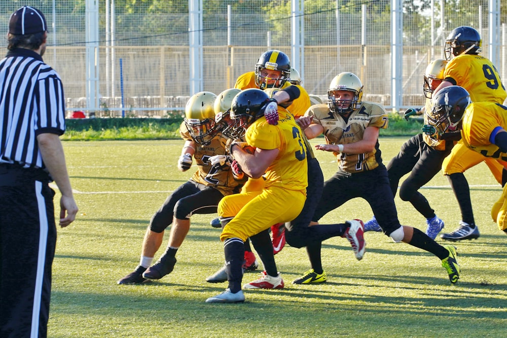 people playing american football with referee on the field during daytime