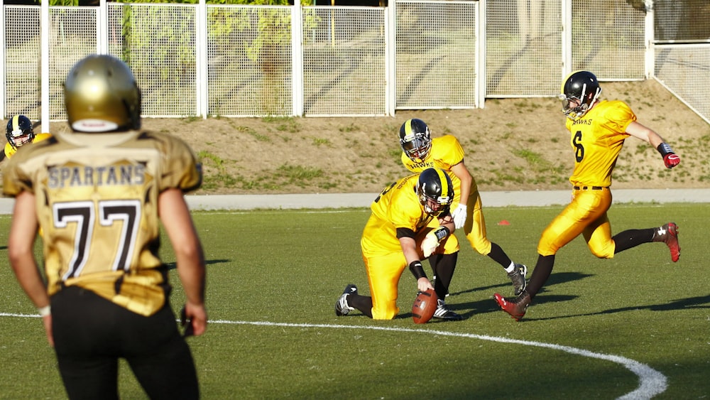 football player about to kick a football held by another player during daytime