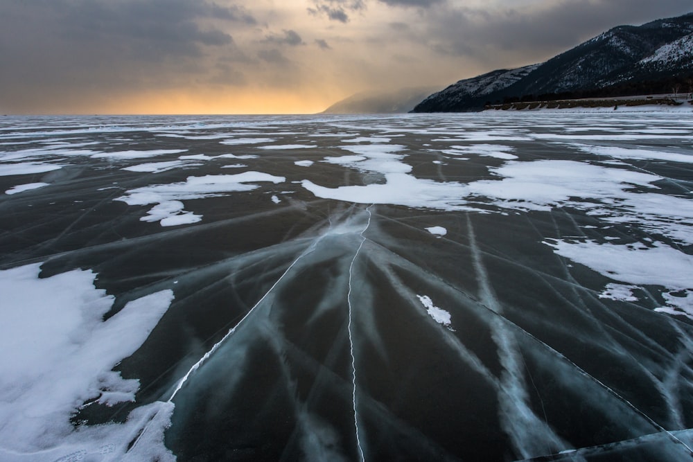 un grand plan d’eau couvert de glace sous un ciel nuageux