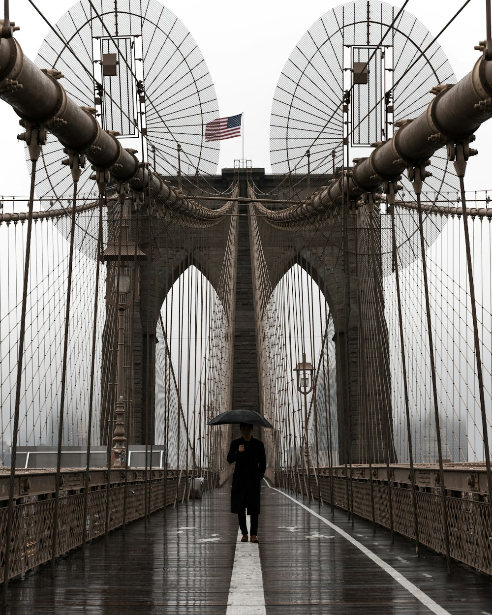 person holding umbrella at Brooklyn Bridge during rainy weather