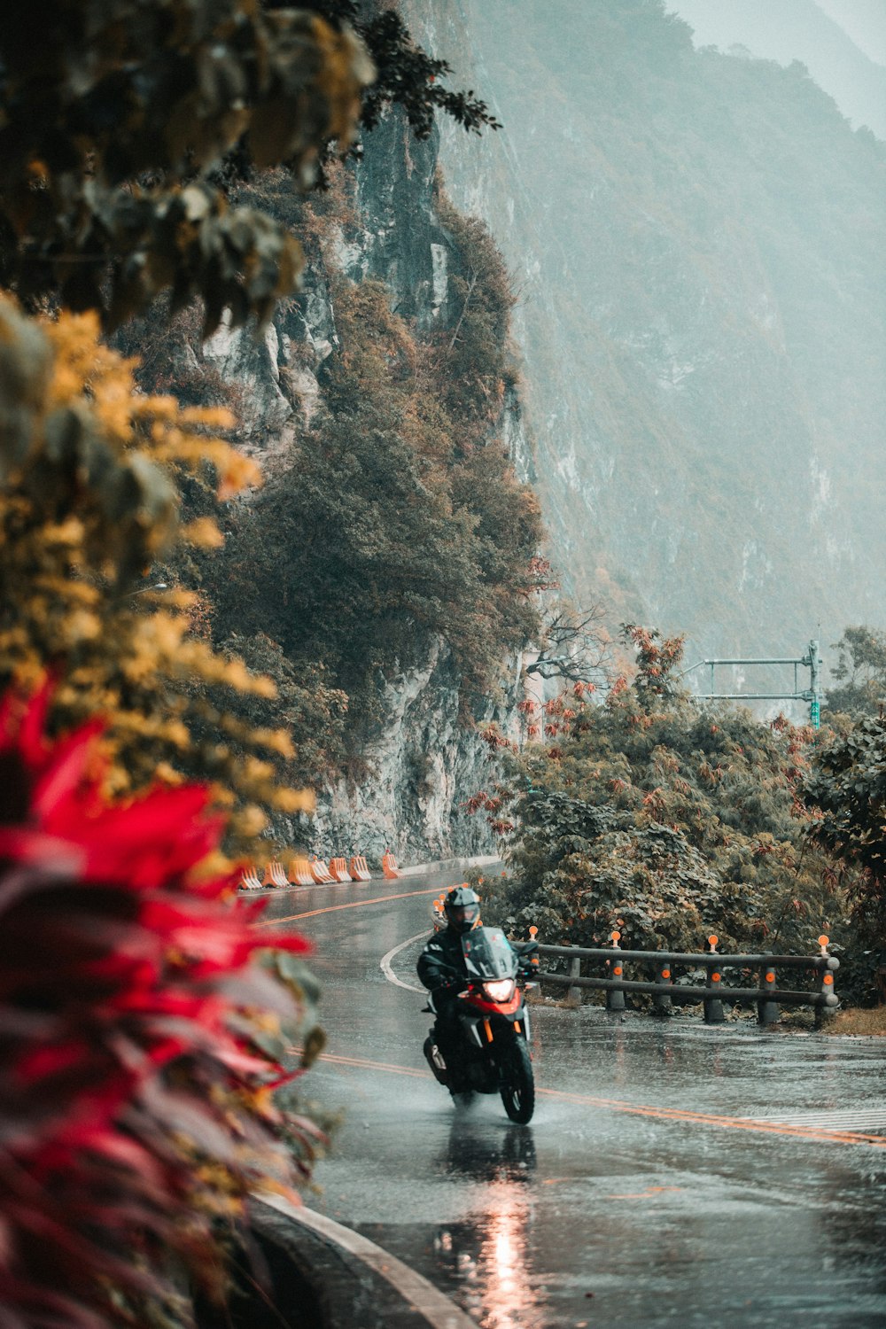 person riding motorcycle passing on road during rainy day
