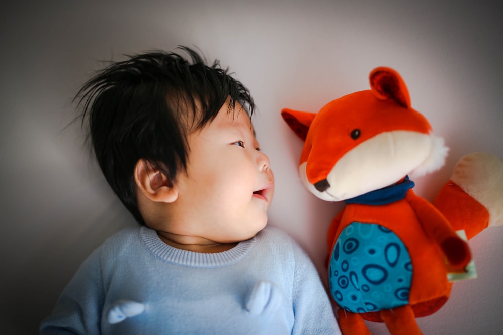 smiling baby looking on reds fox plush toy
