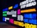Neon signs featuring various motivational words and phrases in English and Chinese. The signs display messages like 'Reach Now,' 'Unconventional,' 'Cutting-Edge,' and 'Always One Step Ahead' in bright colors against a dark background.