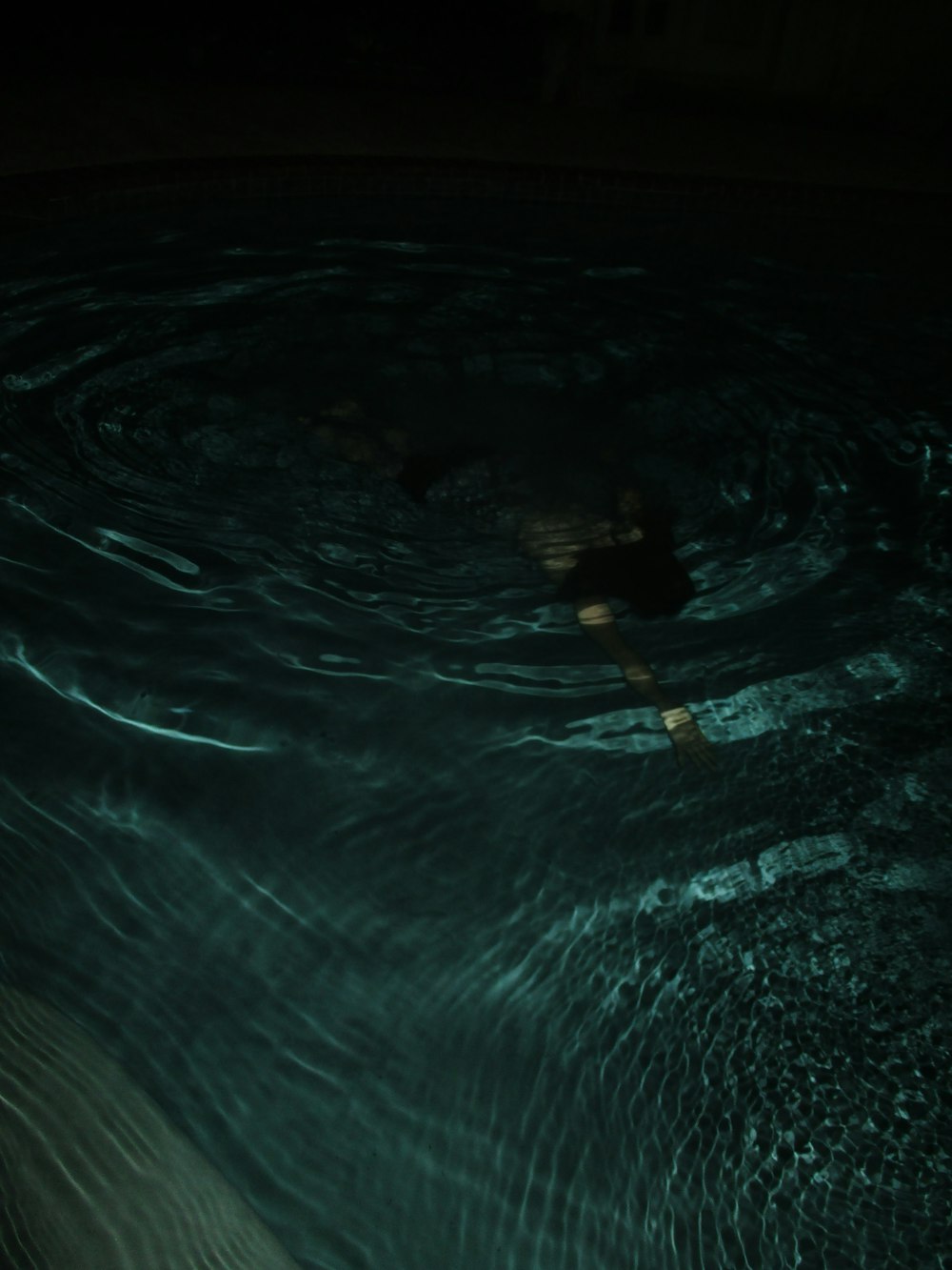 a person floating in a pool of water at night