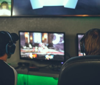 selective focus photography of two persons playing game in front of monitors