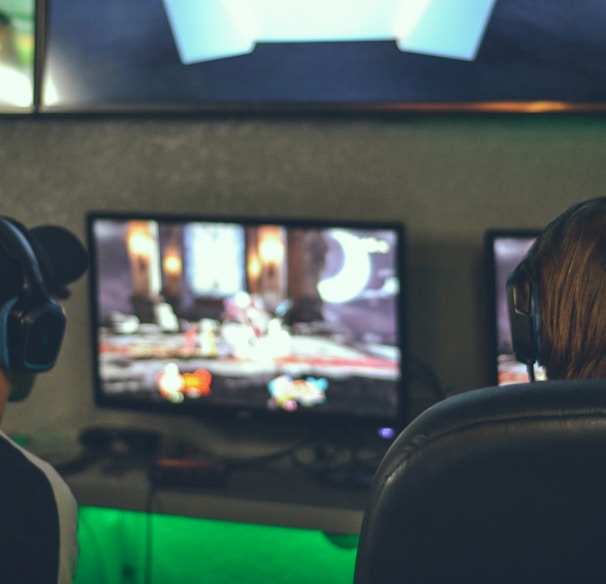 selective focus photography of two persons playing game in front of monitors