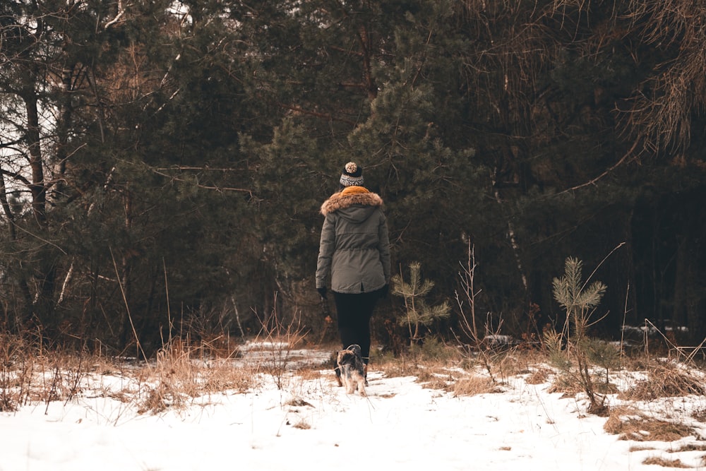 woman walking on snow with her dog