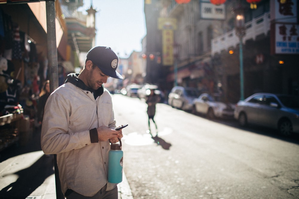 man holding phone beside building