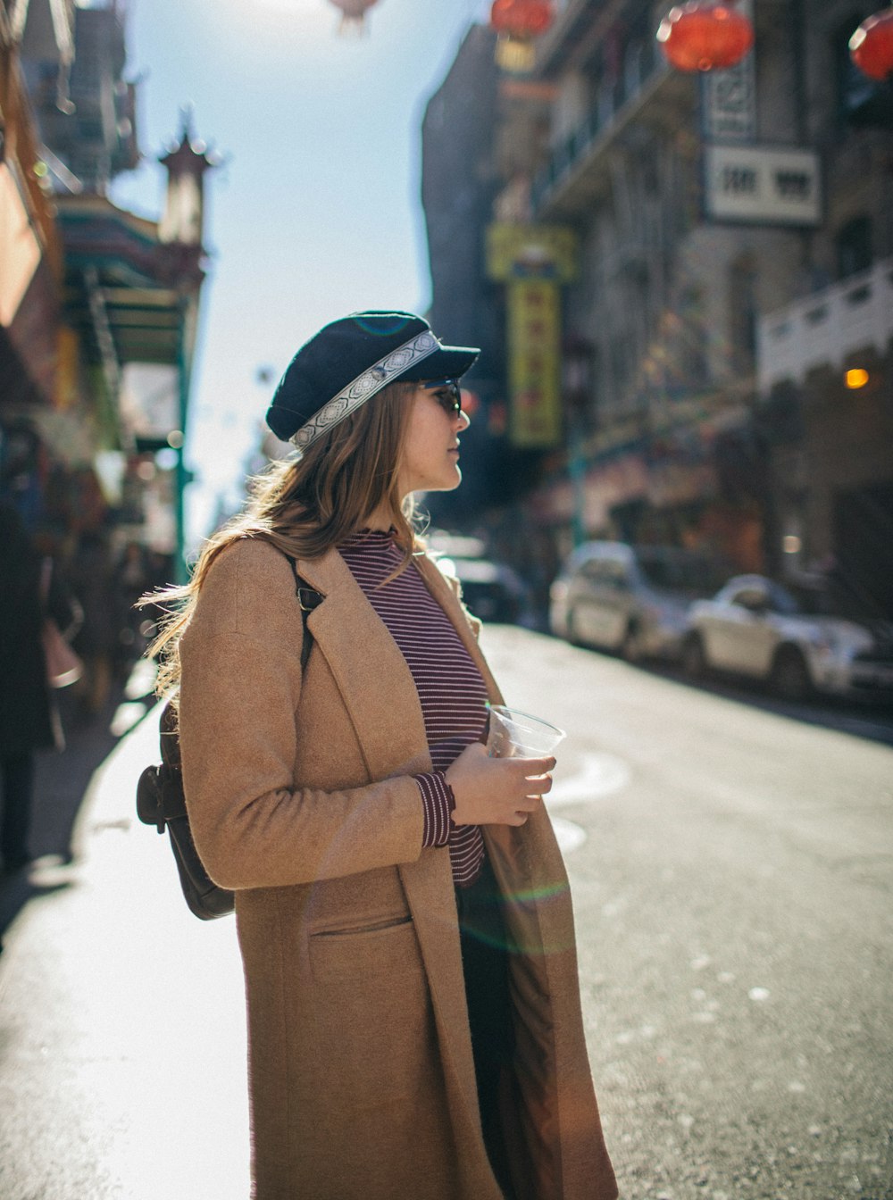 woman in brown coat standing on street during daytime