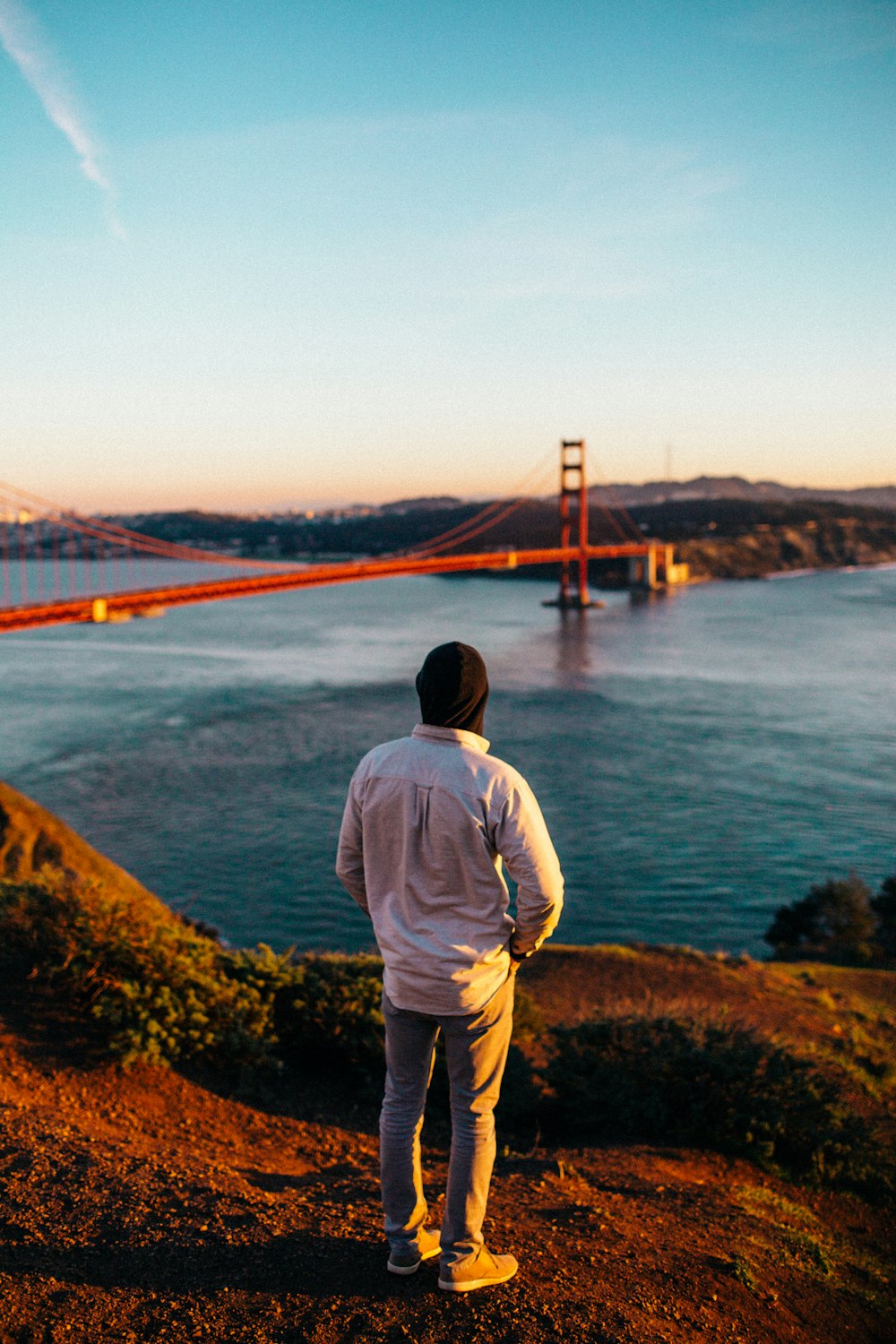 pessoa em pé vestindo jaqueta branca assistindo Golden Gate Bridge