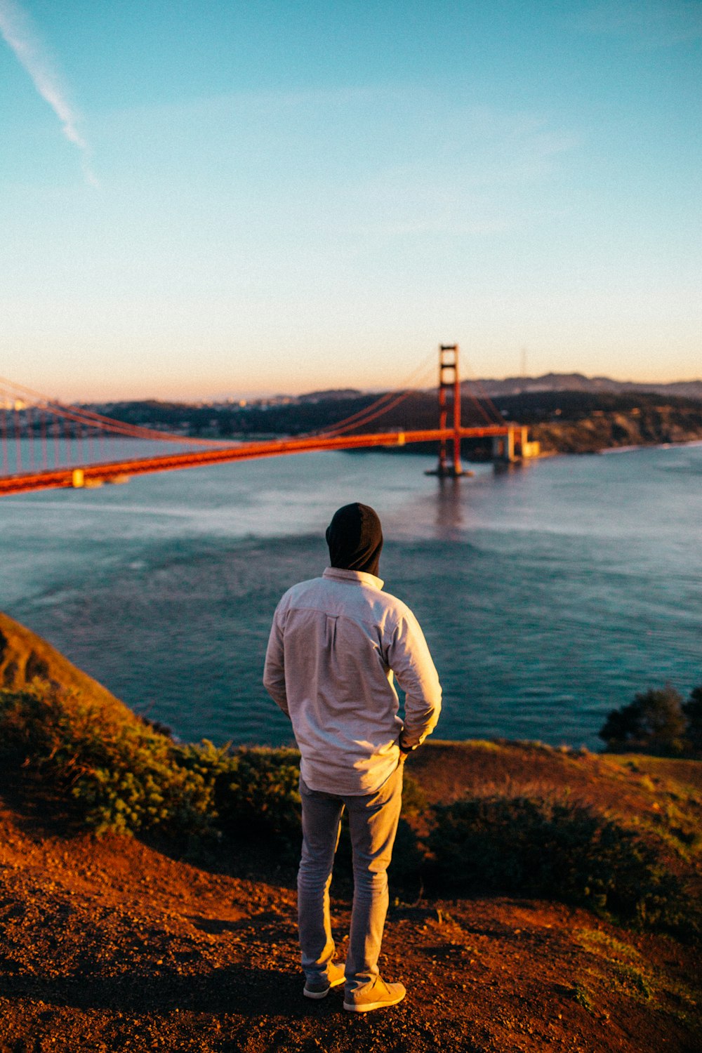 person standing wearing white jacket watching Golden Gate Bridge