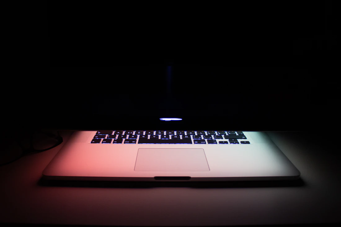 A laptop on a matte black surface displaying a clean website layout.