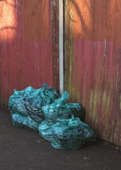 green plastic bags near wooden wall