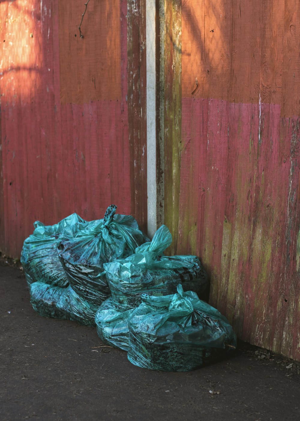 Bolsas de plástico verdes cerca de la pared de madera